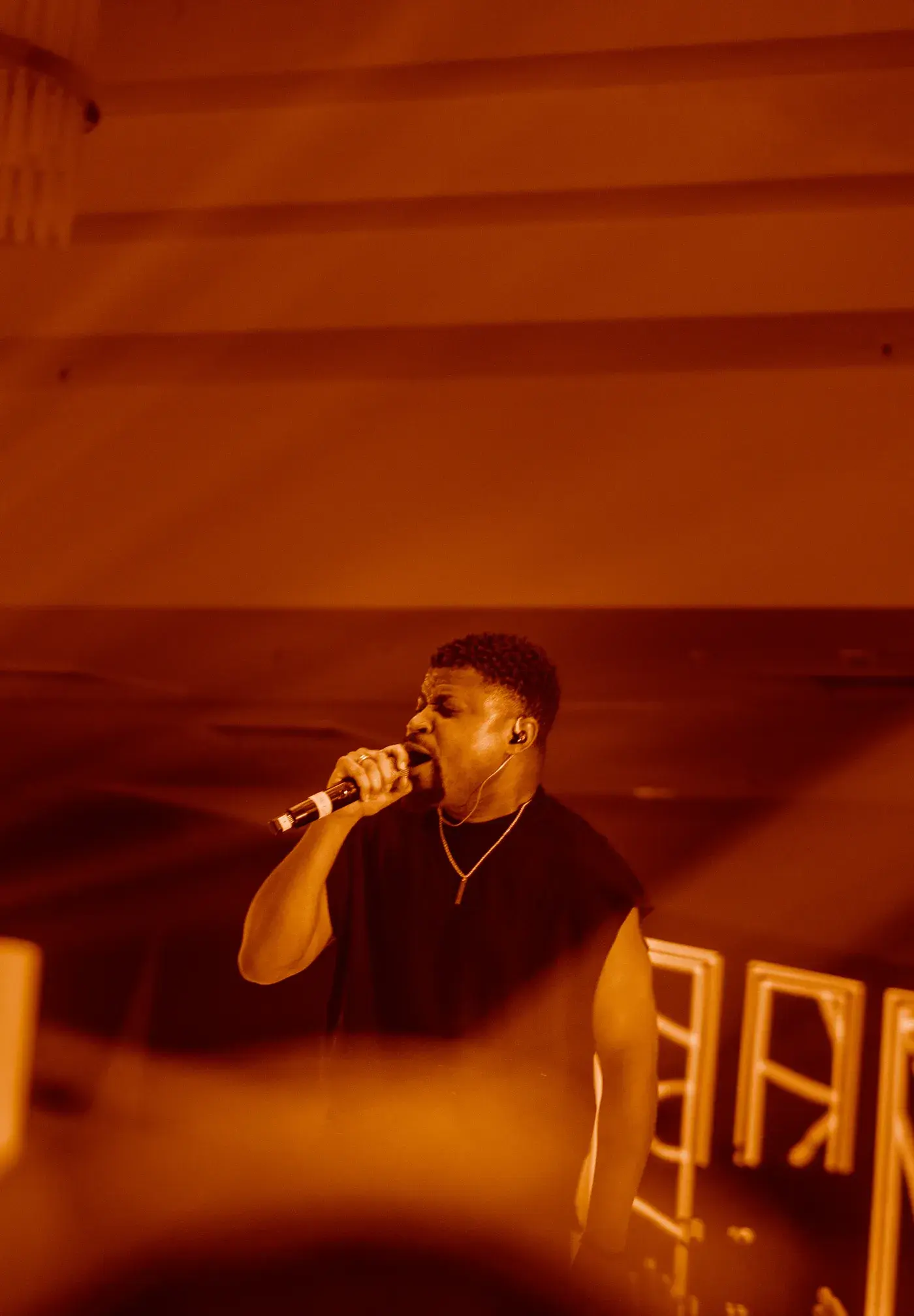 Ko'rale singing into the microphone under warm orange stage light