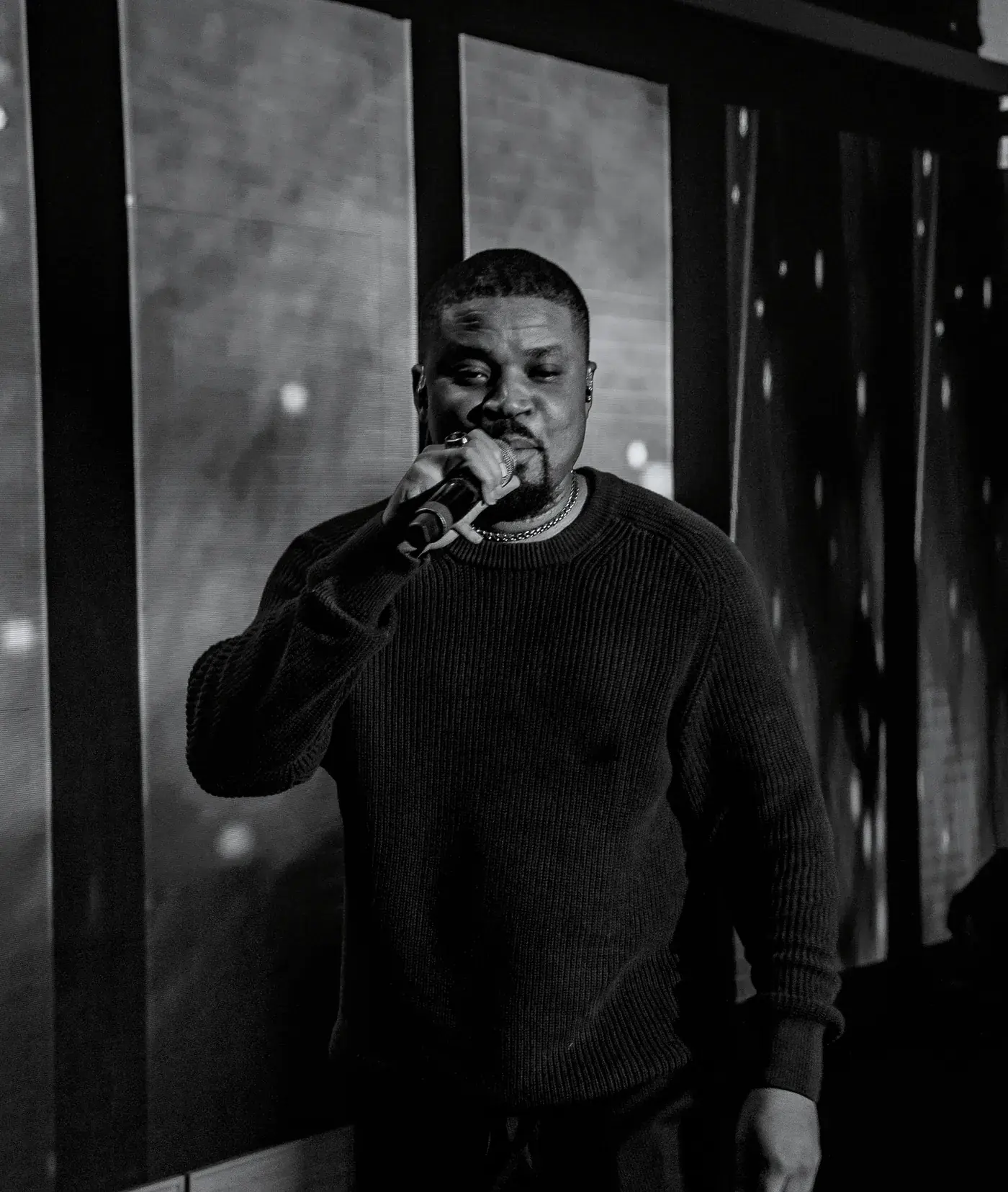 Black and white photograph of Ko'rale performing between lit panels
