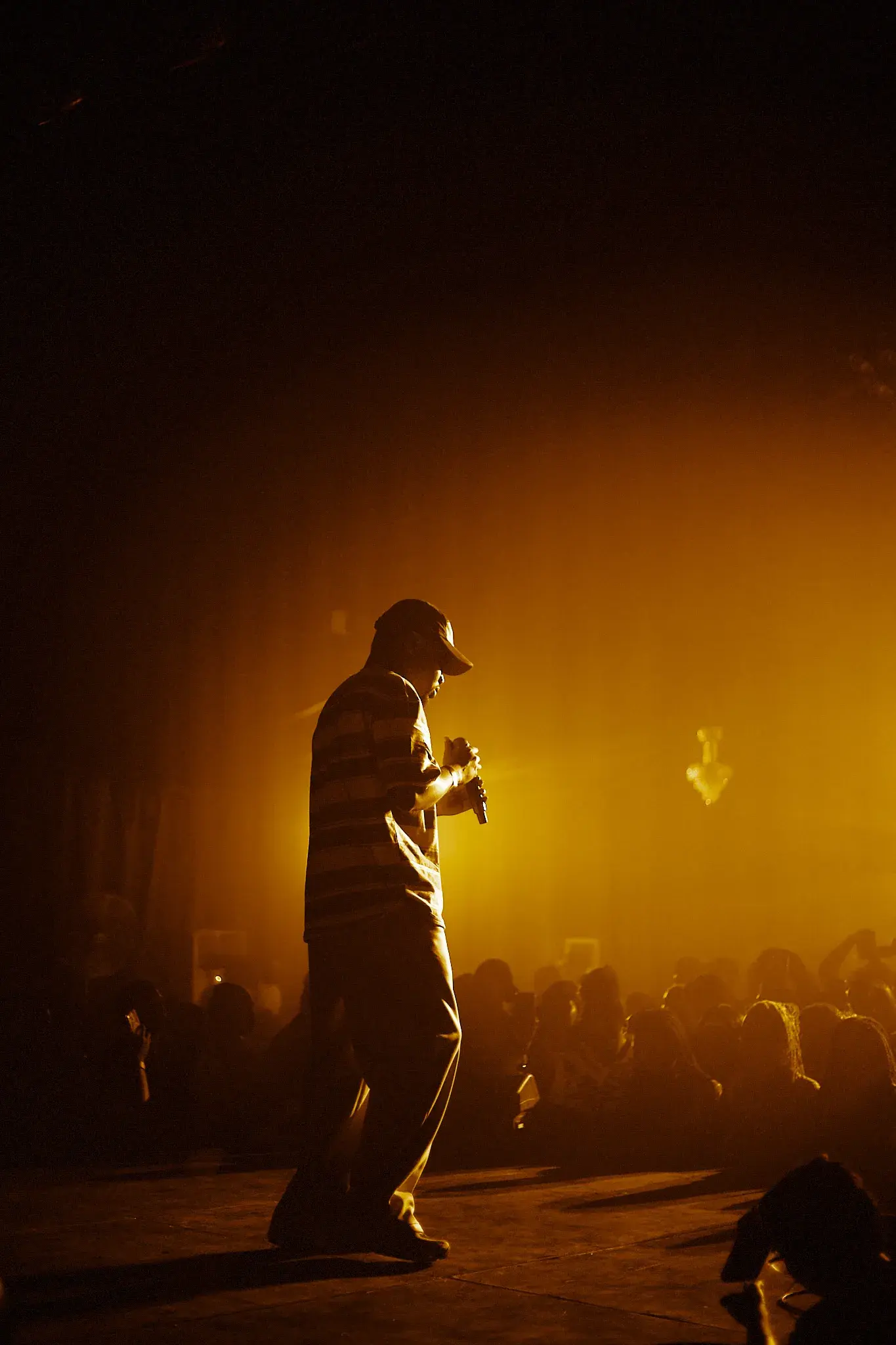 Ko'rale silhouetted in golden stage light as he walks the stage