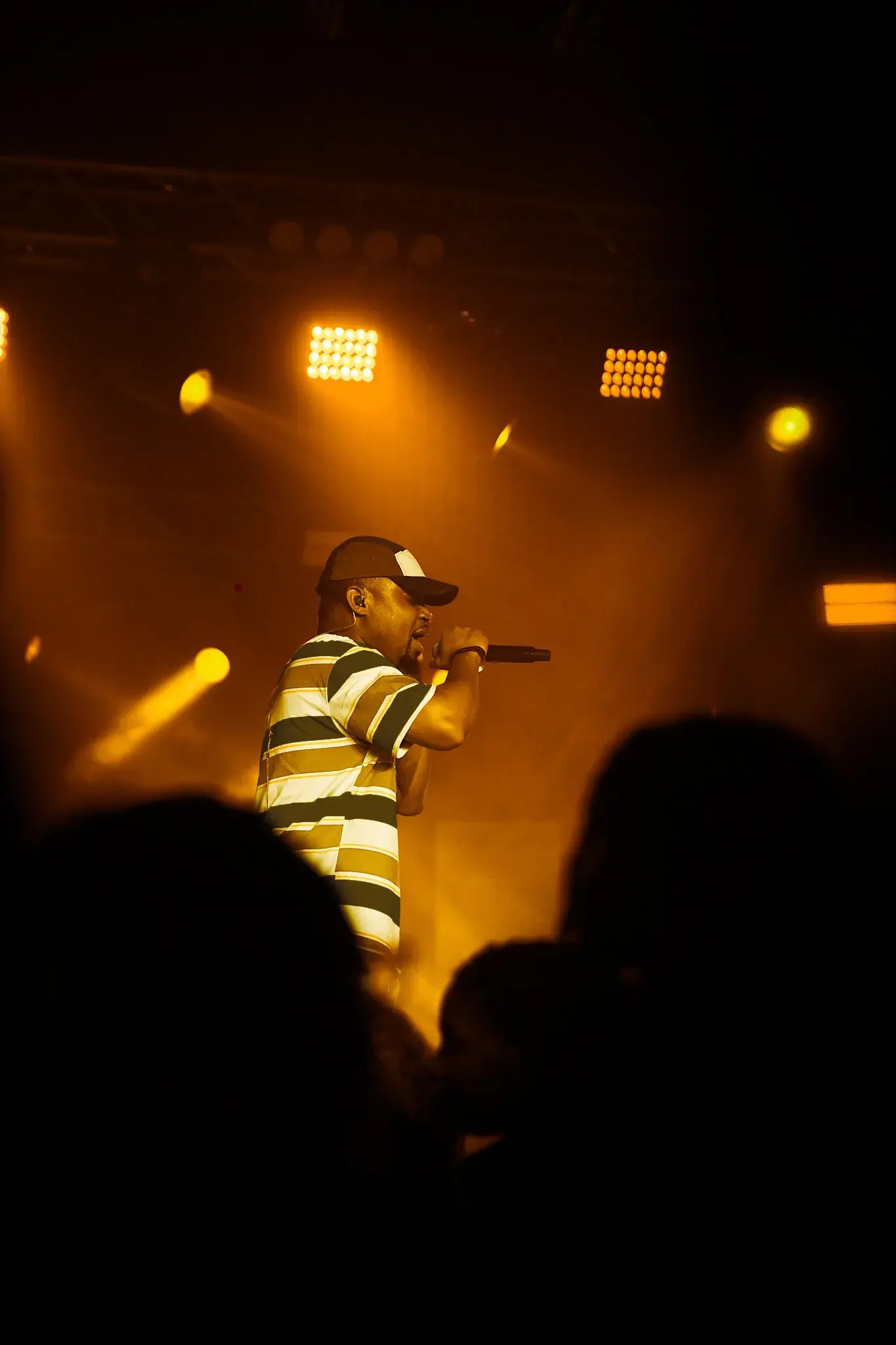 Ko'rale performing on stage in a striped shirt under warm light