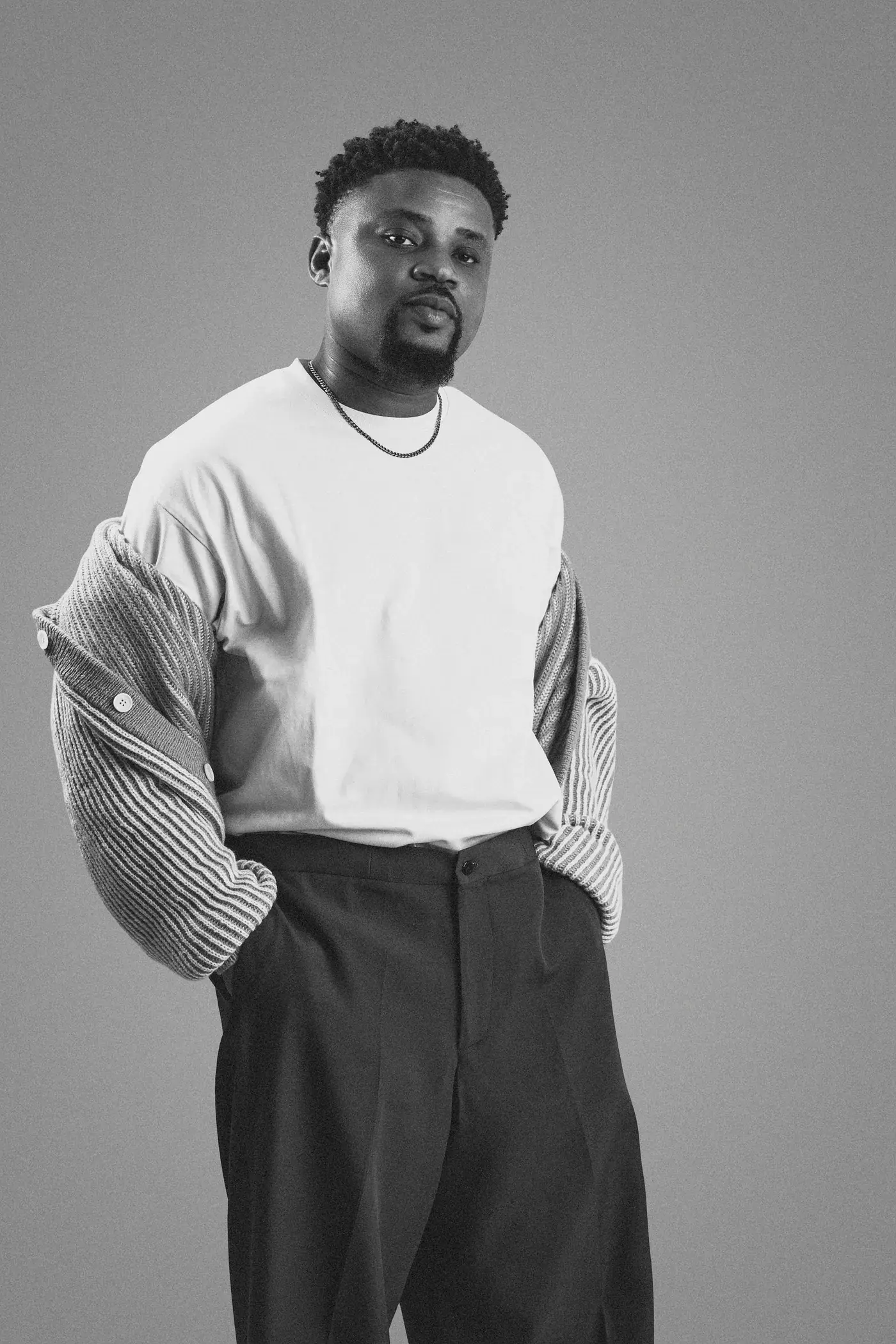 Black and white photograph of Ko'rale with his cardigan pulled off his shoulders